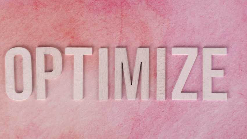 Creative display of the word 'OPTIMIZE' on a pink textured surface.
